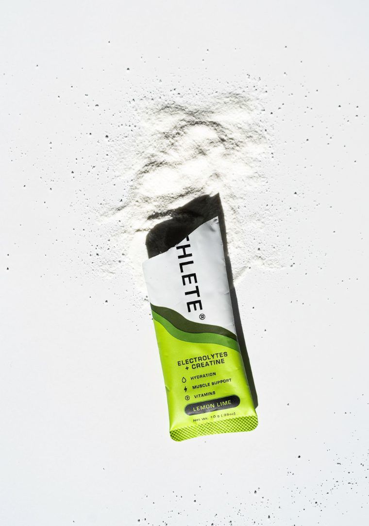 An opened ETHLETE Lemon Lime stick with its powder spilled on a white surface