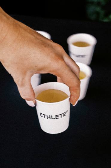 A hand picking up one of several ETHLETE sample cups