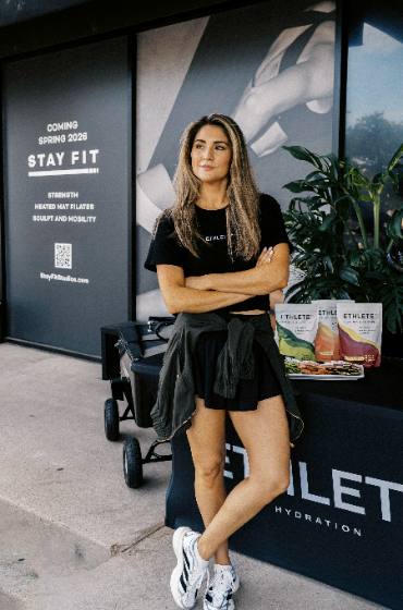 A woman outside the Stay Fit studio beside an ETHLETE sampling stand