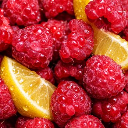 Fresh raspberries and lemon wedges beaded with water