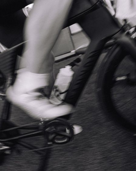 A rider pedalling a bike, in black and white